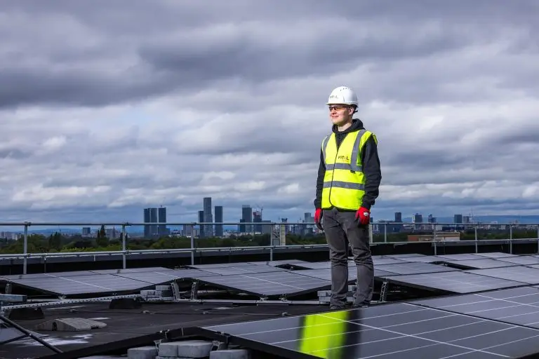 Solar installer standing beside solar panels.